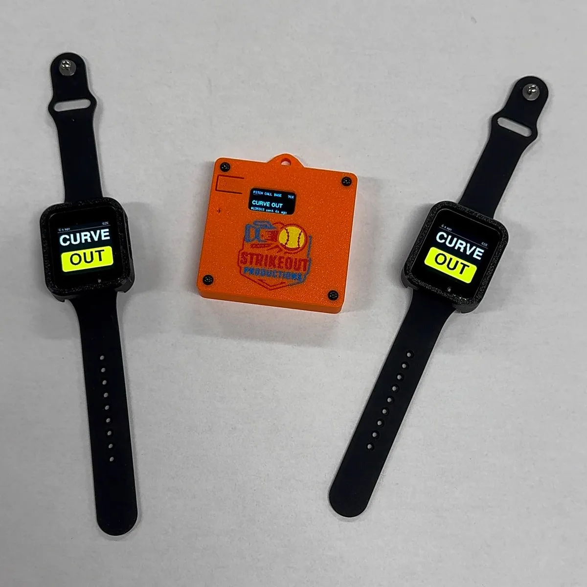 Two watches showing the call CURVE OUT on either side of an orange base unit with the Strikeout Productions logo