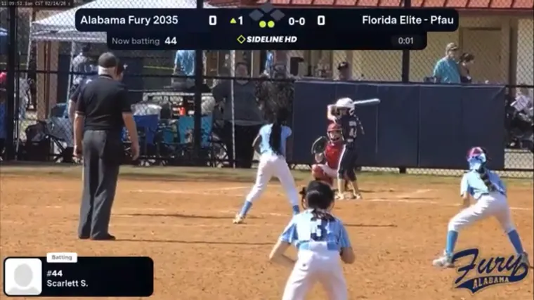 Live broadcast frame from behind the infield as a batter swings, with the scoreboard on screen