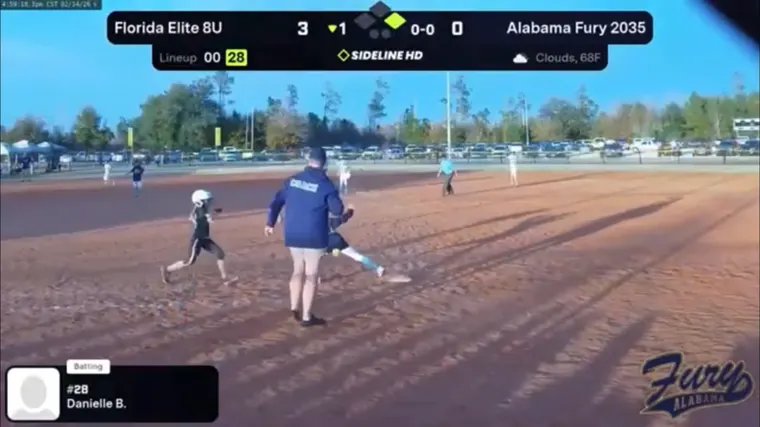 Live broadcast frame of a runner rounding a base past the coach, with the scoreboard on screen