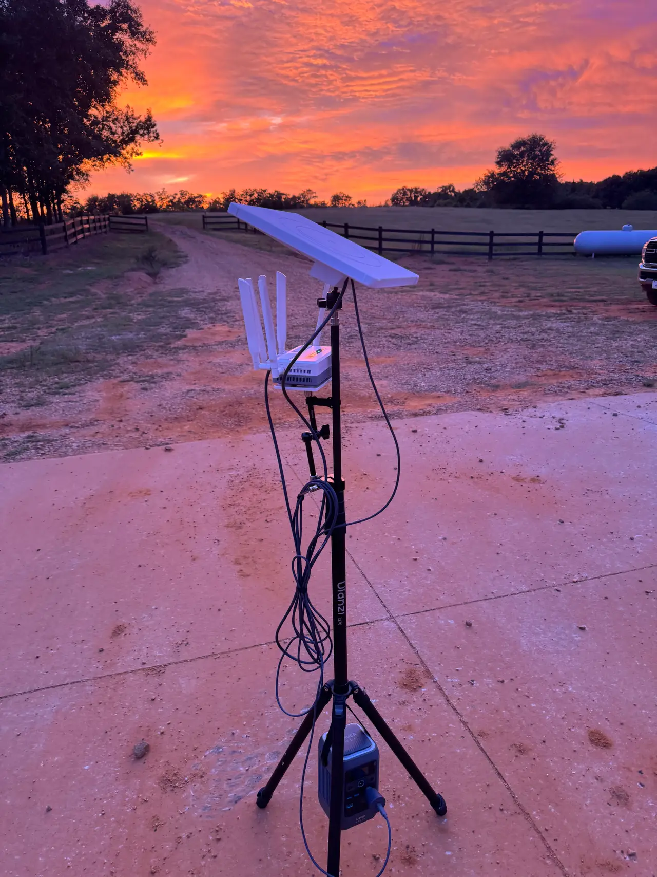 Camera, light panel and battery set up at the field under a burning orange sunset